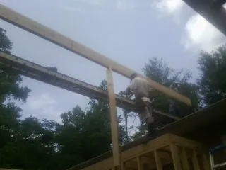 Carpenter setting a ridge beam over a new addition frame — Ice Dam Removal by Roofing Brothers in Seekonk