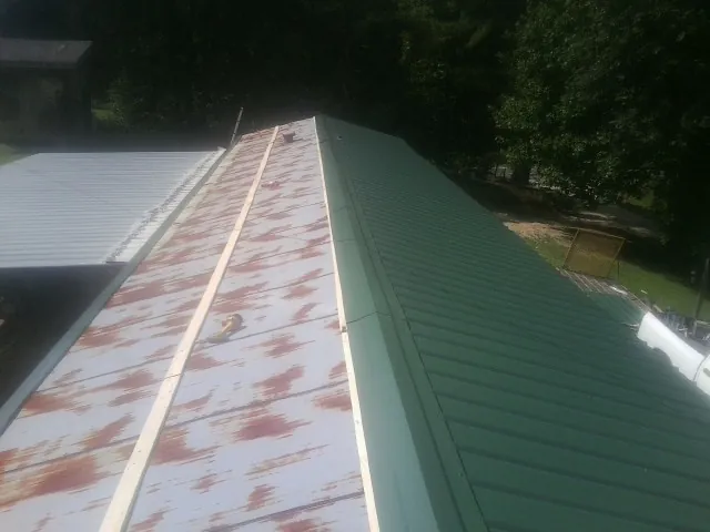 Old rusted panels beside newly installed green metal roofing — Wind Damage Roof Repair by Roofing Brothers in Seekonk