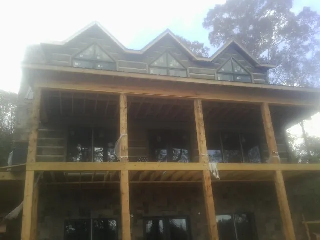 Dormers and porch framing on a large log home under construction — Roof Coating work by our crew in Seekonk