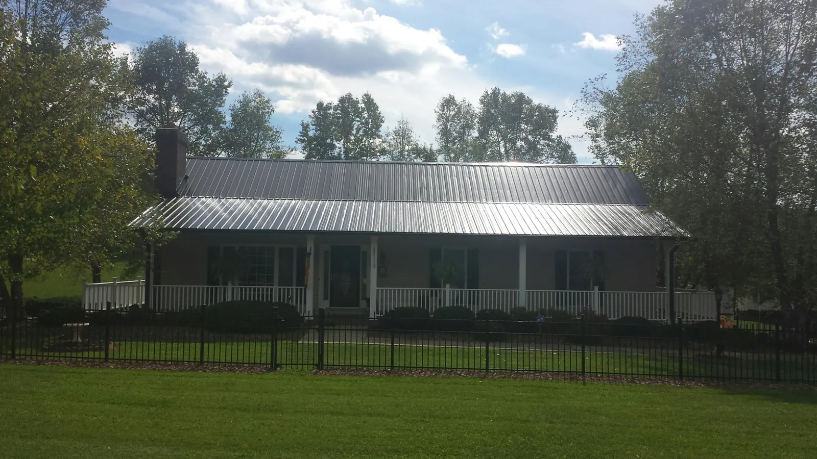 Gray metal roof on a brick ranch with a full width front porch — Gutter Guard Installation work by our crew in Seekonk