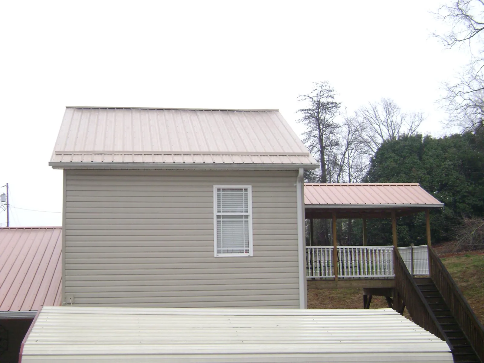 Tan metal roofs on a two story addition and attached porch, from a Roof Replacement job in Seekonk