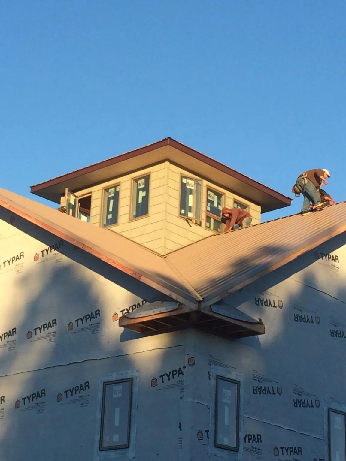 Roofers working around a rooftop cupola on a new metal roof at sunset — Roof Waterproofing in Seekonk by Roofing Brothers
